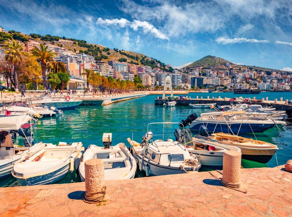 Boats departing Saranda with Corfu visible across the narrow Ionian channel.