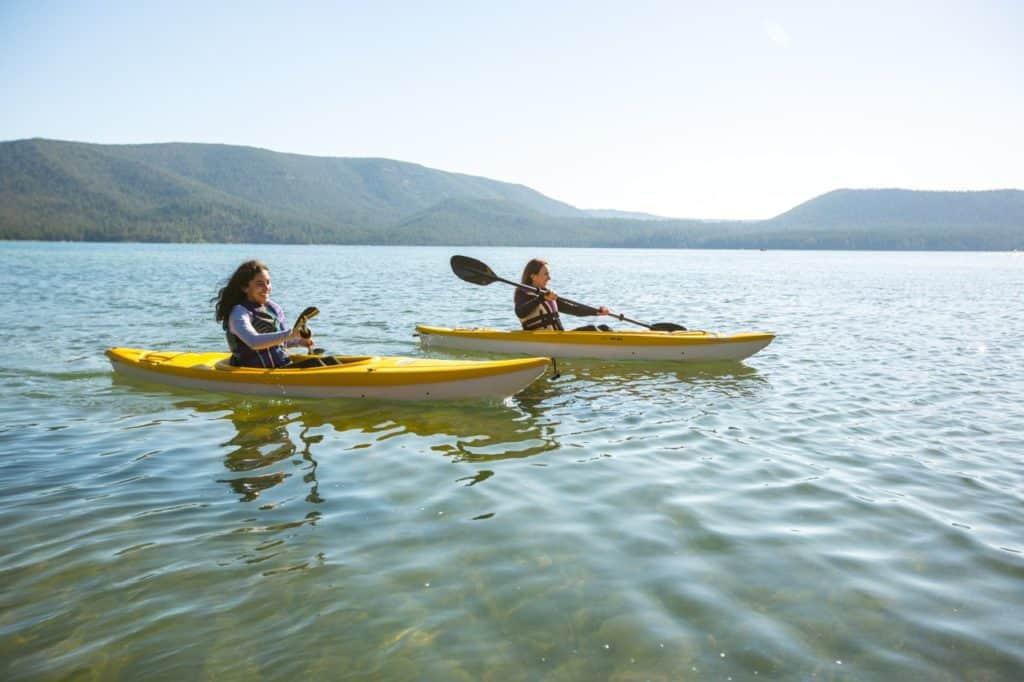 People kayaking on Prineville Reservoir in Oregon's high desert during a calm summer afternoon.