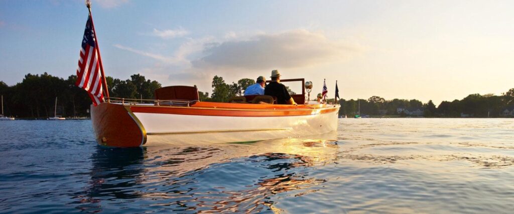 Restored wooden classic boat cruising during golden hour, representing the growing demand for authentic luxury boat charter experiences in America.
