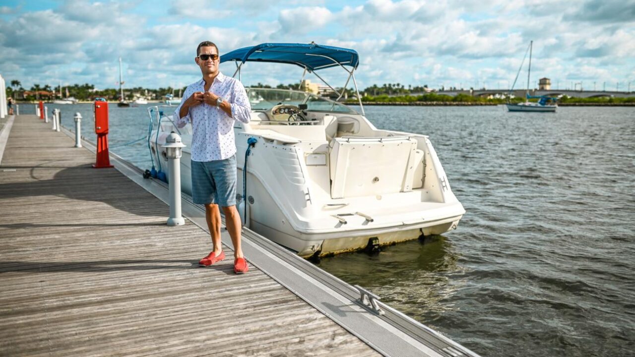 An American boat owner beside a recreational boat in a marina.