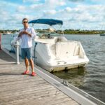 An American boat owner beside a recreational boat in a marina.