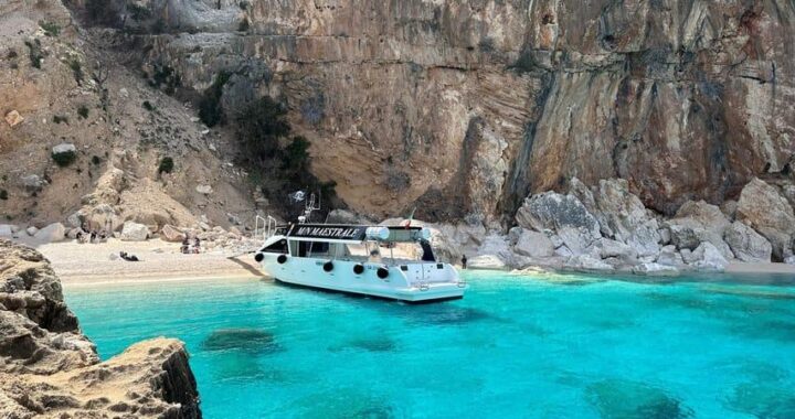 Boat anchored in the turquoise waters of Cala Luna in Sardinia's Golfo di Orosei, accessible only by boat or hiking trail.