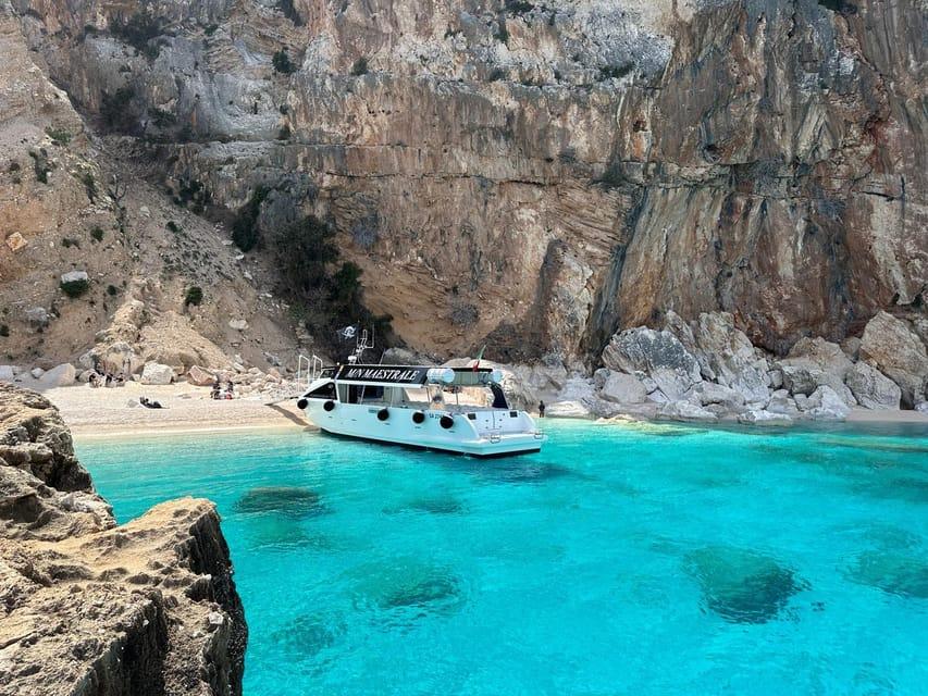 Boat anchored in the turquoise waters of Cala Luna in Sardinia's Golfo di Orosei, accessible only by boat or hiking trail.