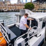 Professional water taxi captain docking a passenger boat at a modern marina.
