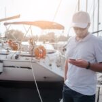 Boat owner creating an online listing for a charter boat using a smartphone at the marina.