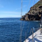 California coastline viewed from a sailboat with dramatic cliffs along the Pacific Ocean.