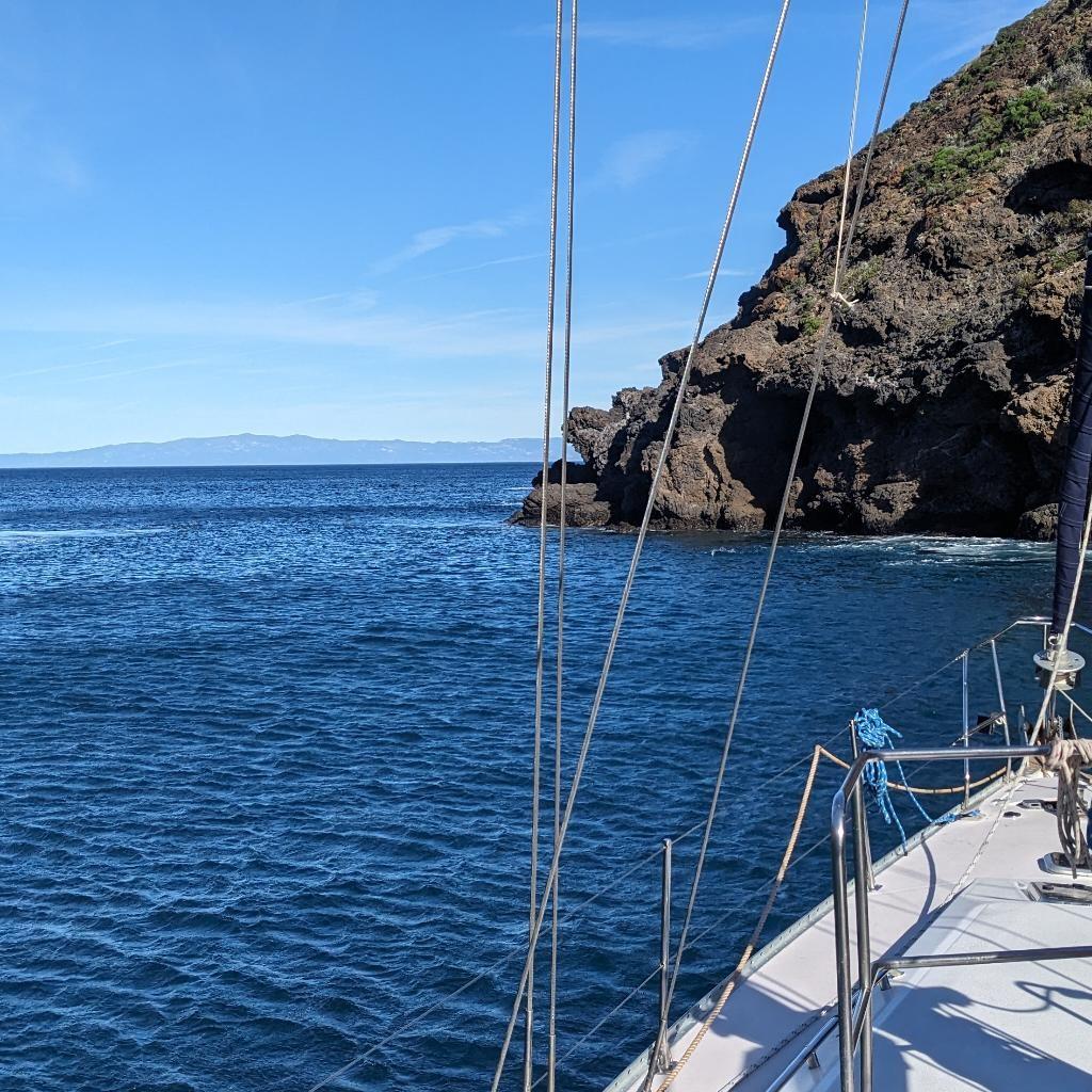 California coastline viewed from a sailboat with dramatic cliffs along the Pacific Ocean.