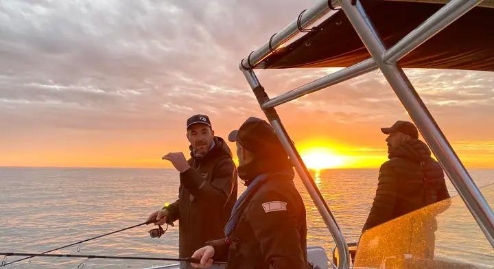 Friends enjoying a sunset fishing charter in Monterey Bay after a day on the water near Santa Cruz, an easy weekend escape from San Jose.