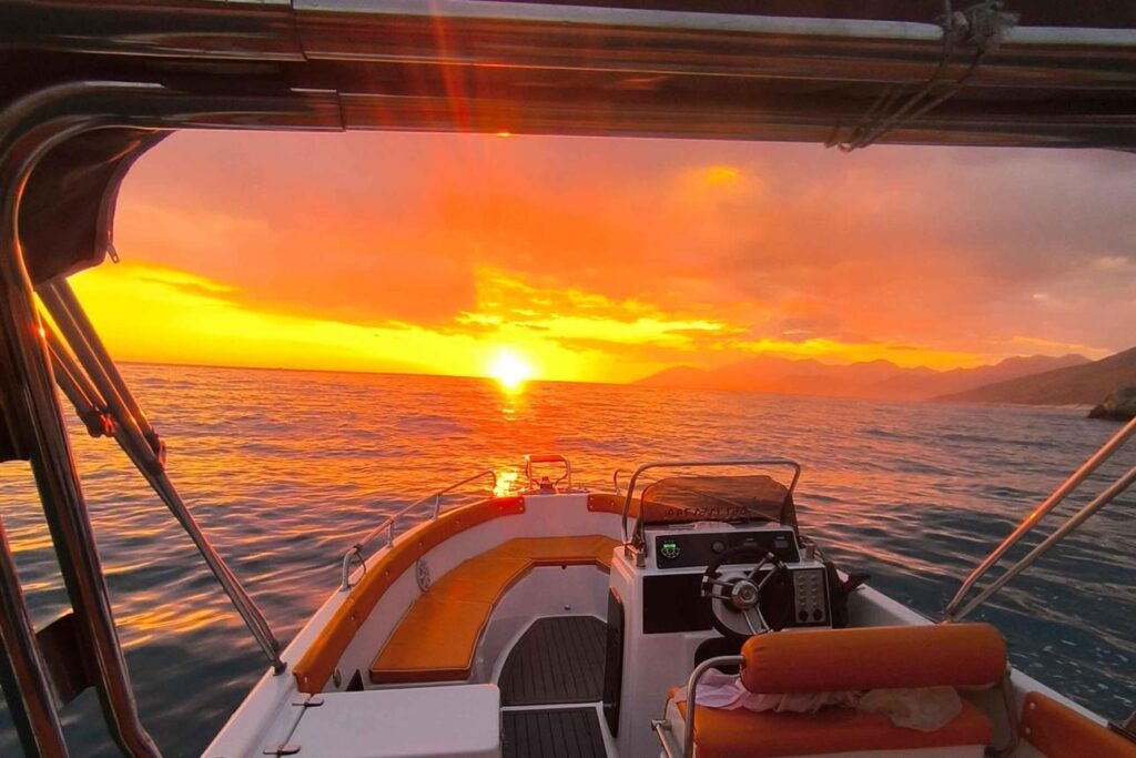 Small boat cruising along the Albanian Riviera at sunset before the coastline becomes more developed.