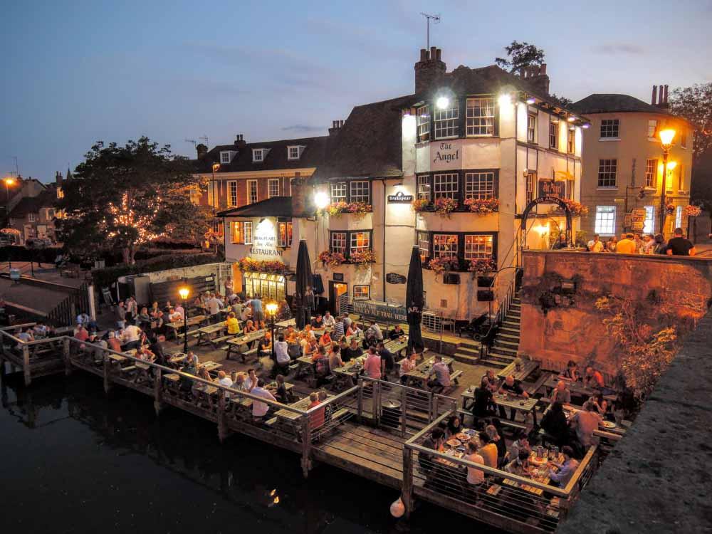 Boat moored beside a traditional riverside pub along the River Thames in England.