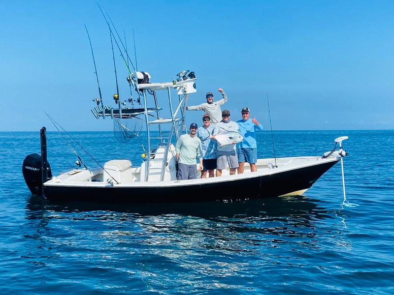 Guests enjoying a successful fishing charter aboard a center console boat.
