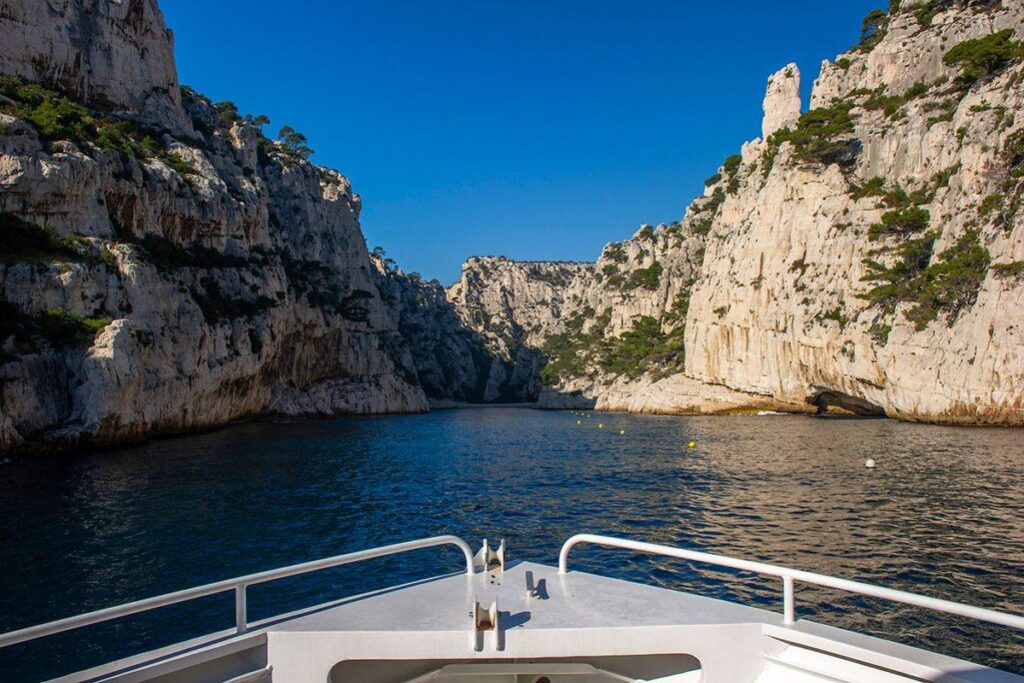 Private boat cruising through the limestone cliffs of the Calanques National Park on the French Riviera.