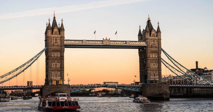 Tower Bridge viewed from a boat cruising along the River Thames at sunset.
