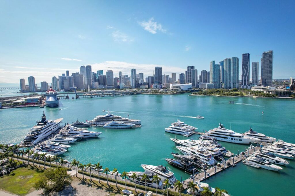 Aerial view of Biscayne Bay filled with private boats and the Miami skyline in the background.