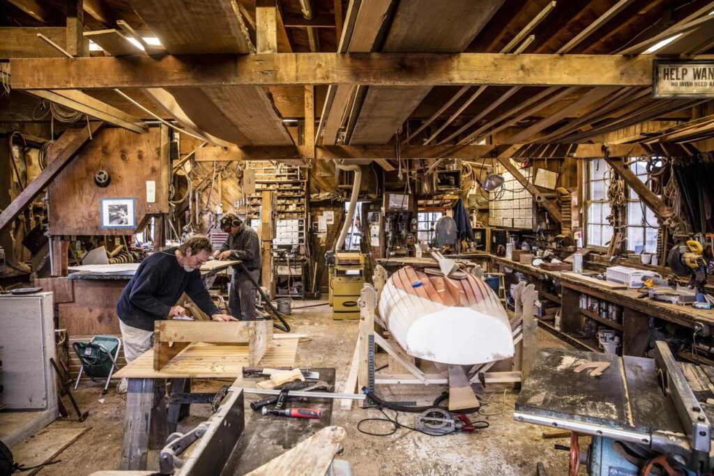 Skilled craftsman restoring the wooden hull of a classic boat before returning it to commercial charter service.