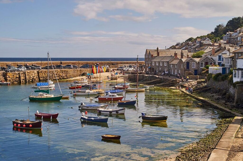 Boat approaching the historic fishing village of Mousehole from the sea on the Cornish coast.