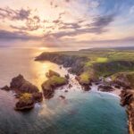 Aerial view of Cornwall's dramatic coastline and turquoise waters near Kynance Cove.